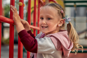 Kids play on the playground. Happy laughing girl have fun swinging and climbing outdoor