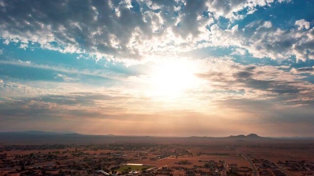 Sun rays break through the drifting clouds during a golden sunrise over California City in the Mojave Desert - high altitude time lapse