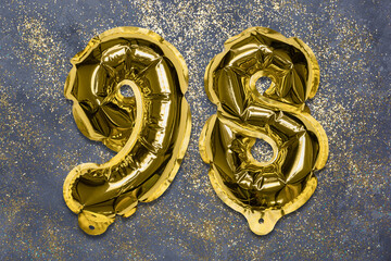The number of the balloon made of golden foil, the number ninety-eight on a gray background with...