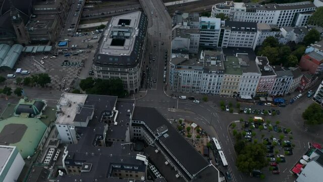 Tilt down reveal of cars driving through crossroad in city. Wide multilane streets leading between tall town buildings. Free and Hanseatic City of Hamburg, Germany