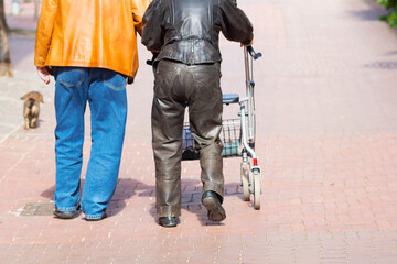 Laborious walk - Woman with walker and a man and dog in the city 