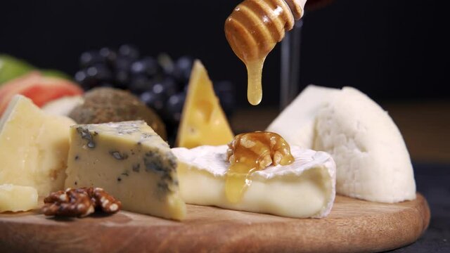 Cheese plate served with grapes and nuts. Assorted cheeses camembert, brie, parmesan blue cheese, goat with grapes, gressini sticks, cashews, honey and jam.