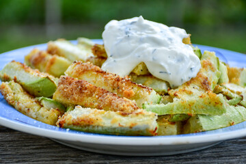 Home made keto   organic fried zucchini sticks with parmesan cheese and almond flour   and garlic yogurt sauce on wooden background. Ketogenic diet food