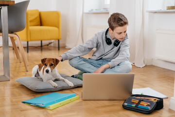 Young boy doing his homework with his pet dog