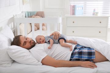 Tired young father sleeping with his baby in bed at home