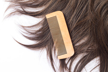 Straight brown hair with wooden comb isolated on white background