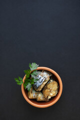 Mackerel fish in pieces on a clay plate. Black background and vegetables. Healthy food concept