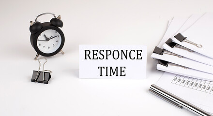Card with text RESPONCE TIME on a white background, near office supplies and alarm clock. Business...