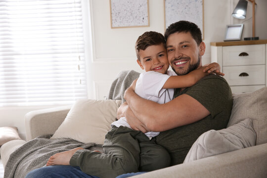 Father and his son on sofa in living room. Adoption concept - Powered by Adobe