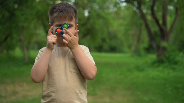 Kid Holding Rainbow Pop It Fidget Toy in hands. Child is Playing Trendy Popular Board Game Anti-Stress Toy Pop It (Popit or Simple Dimple). Jule 2020. Kyiv, Ukraine. High quality 4k footage