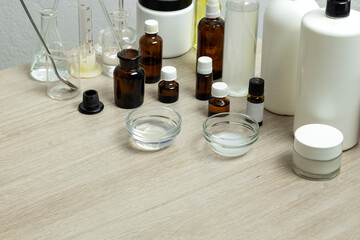 Lot of glass bottles and glassware for elaborating cosmetic ingredients, wooden lab table.Empty...