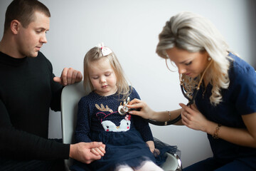 Father with girl being examined by female pediatrician in clinic