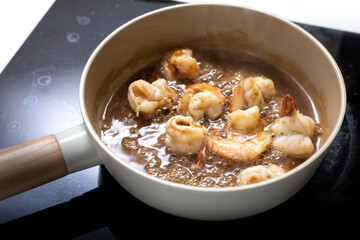 homemade stir fried shrimp with oyster sauce in pan on induction stove or cooktop, gourmet food recipe, good work from home lunch idea, shallow depth of field