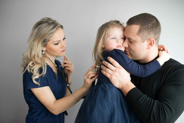 Father with girl being examined by female pediatrician in clinic