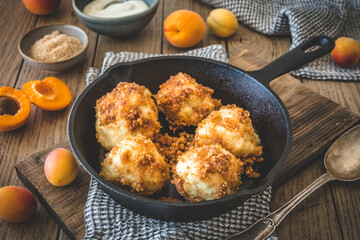 Sweet dumplings with sweet breadcrumbs, filled with apricots, on wooden table