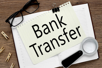 Bank Transfer. notepad with text on a wooden table. notebook near black glasses