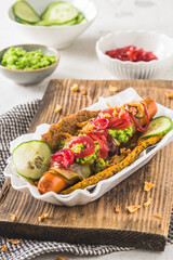 Healthy vegetarian hot dog with flatbread made from vegetables, topped with red onions, pickles and pea puree, vertical