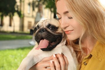 Woman with cute pug dog outdoors on sunny day, closeup. Animal adoption