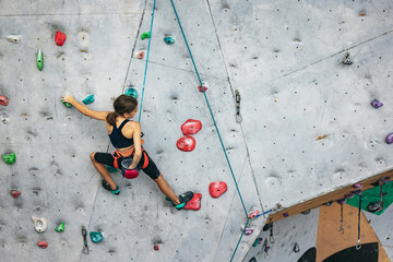 One cute teen girl practicing on the rock wall in climbing center. Concept of sportive lifestyle,...