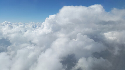 white gray fluffy clouds under blue sky - from airplane window
