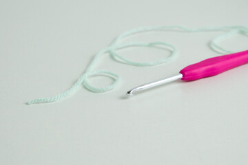 knitting pink crochet hooks and woolen thread on a blue background