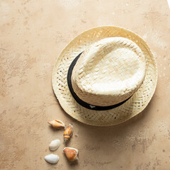 Top view ofstraw hat  and seashells on beige  background.  Summer time  and tropical vacation concept.