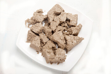 Large pieces of halva lie on a porcelain plate on a white background.