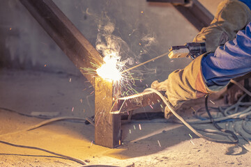 Man welder assembles a metal staircase structure in a residential building using a welding machine.