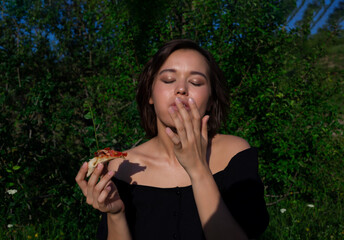 portrait of a young beautiful woman eating pizza