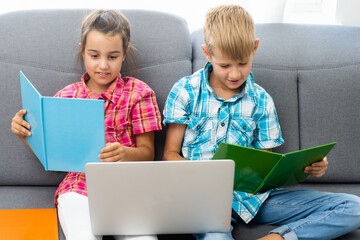 Young boy with a laptop computer sitting near a girl
