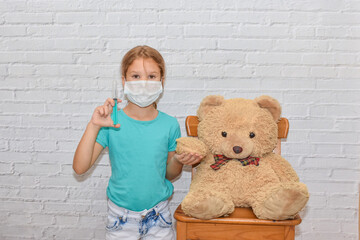 the child girl with a syringe makes an injection vaccination toy bear photo without processing