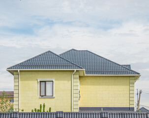 House with a new metal roof against a blue sky closeup. Roof from corrugated board