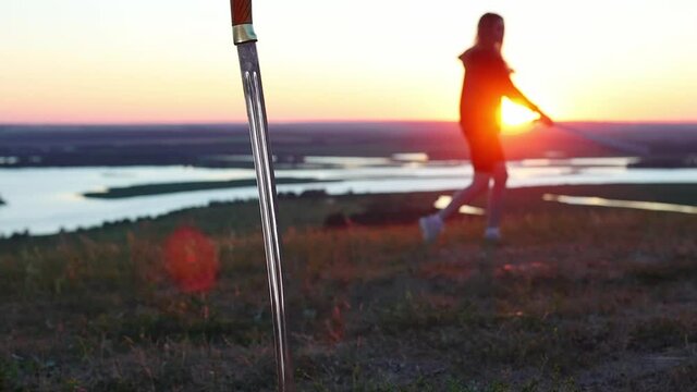 Swords training - young woman training on nature while sunset - second sword drove into the ground