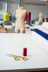 Sewing factory concept. Spools of thread and basic sewing tools including pins, needle, a thimble, and tape measure.