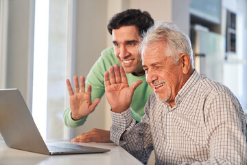 Senior und junger Mann winken beim Video Streaming