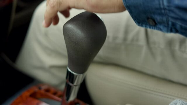Close up shot Young man hand control the stick shift transmission in luxury car. Male hand changing gear driving car.