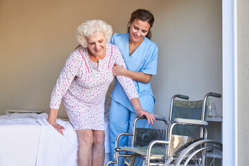 Altenpflegerin hilft Seniorin beim Aufstehen aus dem Bett