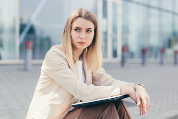 Worried business woman sitting near office center with laptop