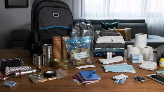 Emergency backpack equipment organized on the table in the living room. Left to right panning