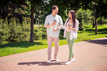 Photo of charming sweet family wear casual clothes smiling walking drinking tea outdoors urban city park