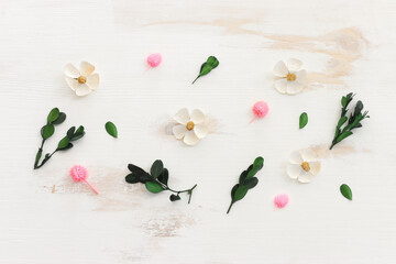 Top view image of pink, white, green and pink flowers composition over white wooden background .Flat lay