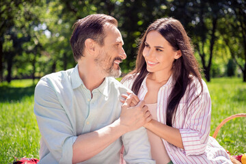 Photo of cute pretty husband wife dressed casual outfit sitting green grass holding arms smiling outside urban city street