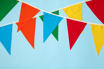 Fototapeta na wymiar Buntings with colorful triangular flags on light blue background. Festive decor