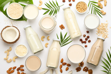 Fototapeta na wymiar Different vegan milks and ingredients on white background, flat lay