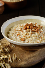 Oatmeal porridge with almonds and some ears of oats closeup. Healthy eating. Vegan and vegetarian food.