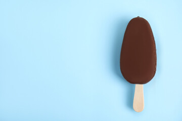 Ice cream glazed in chocolate on light blue background, top view. Space for text