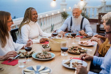 Fototapeta na wymiar Senior multiracial people having fun at patio dinner - Focus on african woman face