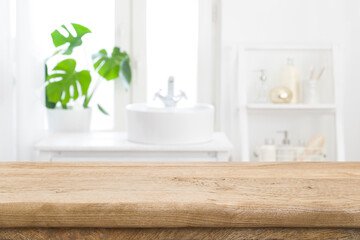 Empty wooden table top with blurred bathroom sink interior background