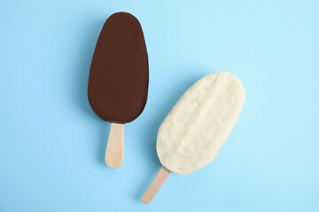 Glazed ice cream bars on light blue background, flat lay