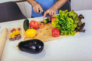 cooking and home concept - close up of male hand cutting vegetables on cutting board with sharp knife